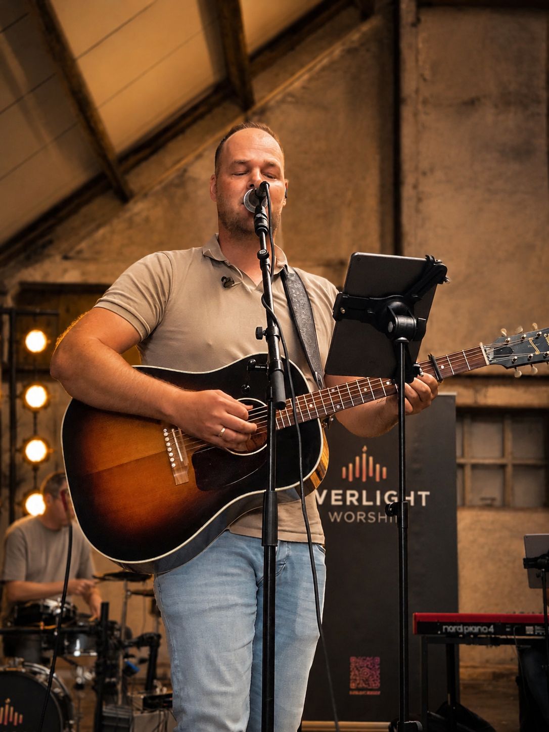 Zanger met akoestische gitaar voor de banner van Everlight Worship